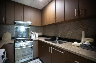 a kitchen with wooden cabinets and a stove and a sink at Noma Fairview - Burj Khalifa view stunning apartment in Business Bay in Dubai