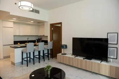 a living room with a large television and a kitchen at Fabulous Canal Views Al Habtoor City in Dubai