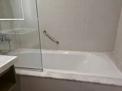 a shower with a glass door and a white tub at LeModCasa - Modern Chic studio in Dubai