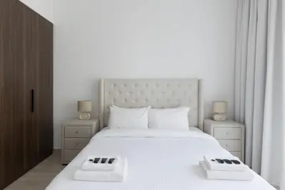 a bedroom with a large white bed with two night stands at 1BD Partial Burj Al Arab View Prime Location in Dubai