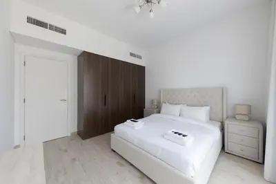a white bedroom with a white bed and a wooden door at 1BD Partial Burj Al Arab View Prime Location in Dubai