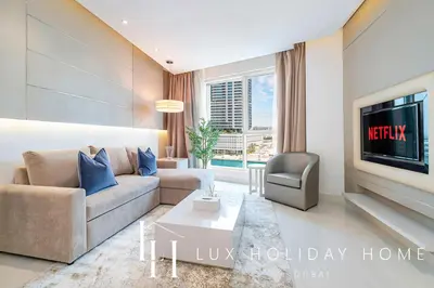 a living room with a couch and a tv at LUX The Voleo Canal View Suite in Dubai