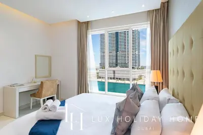 a bedroom with a bed and a desk and a window at LUX The Voleo Canal View Suite in Dubai