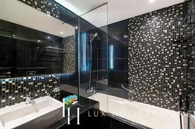 a bathroom with a sink and a glass shower at LUX The Voleo Canal View Suite in Dubai