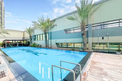 a large swimming pool with palm trees in front of a building at LUX The Voleo Canal View Suite in Dubai