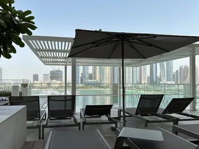 a patio with chairs and an umbrella and water at Trophy Luxury 1BDR in Emaar Beach Front with Panoramic Sea Views from the Apartment and Private Beach Access in Dubai