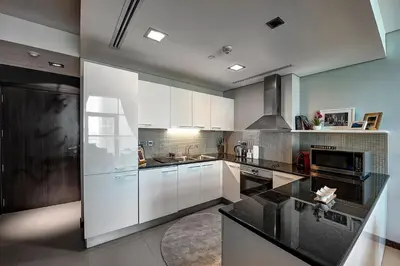 a kitchen with white cabinets and a black counter top at Blueground DIFC marina view pool gym DXB-21 in Dubai