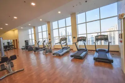 a gym with cardio equipment in a large room with windows at Blueground DIFC swimming pool gym security DXB-1545 in Dubai