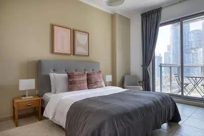 a bedroom with a large bed and a large window at Blueground The Residences gym parking DXB-1348 in Dubai