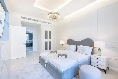 a white bedroom with a bed and a chair at Palm Home next to Nakheel Mall with Private Beach in Dubai