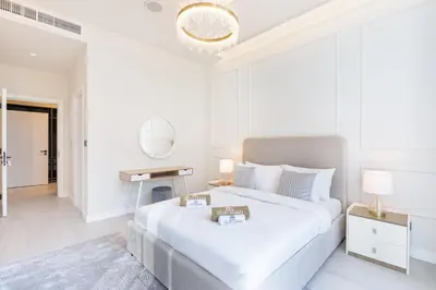 a white bedroom with a large bed and a mirror at Palm Home next to Nakheel Mall with Private Beach in Dubai