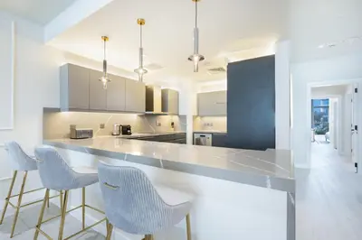 a kitchen with a counter and stools in it at Palm Home next to Nakheel Mall with Private Beach in Dubai