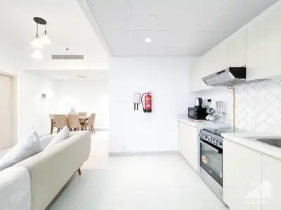 a white kitchen with a couch and a table at Luxurious 1BR Apt with Balcony in Production City in Dubai