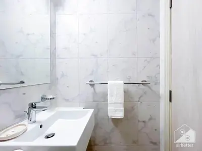 a white bathroom with a sink and a mirror at Luxurious 1BR Apt with Balcony in Production City in Dubai