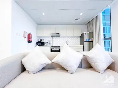 a living room with a couch with four pillows at Luxurious 1BR Apt with Balcony in Production City in Dubai