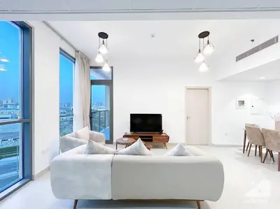 a living room with a white couch and a television at Luxurious 1BR Apt with Balcony in Production City in Dubai