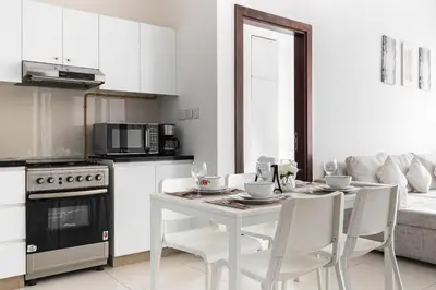 a white kitchen with a white table and chairs at Binghatti Gateway Family 2BR with Balcony, Close to Dubai Mall & Burj Khalifa by Simply Comfort in Dubai