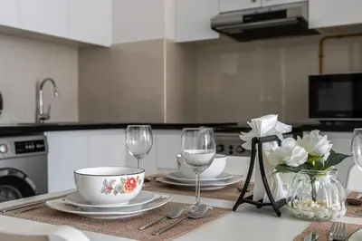 a kitchen table with two plates and wine glasses at Binghatti Gateway Family 2BR with Balcony, Close to Dubai Mall & Burj Khalifa by Simply Comfort in Dubai