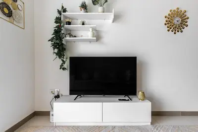 a white living room with a flat screen tv on a white wall at Binghatti Gateway Family 2BR with Balcony, Close to Dubai Mall & Burj Khalifa by Simply Comfort in Dubai