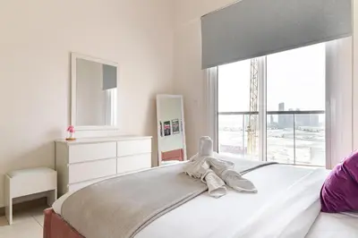a white bedroom with a bed with a large window at Binghatti Gateway Family 2BR with Balcony, Close to Dubai Mall & Burj Khalifa by Simply Comfort in Dubai