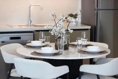 a table with chairs and plates and a vase with flowers at High-Rise Chic, Burj Crown, Opera Boulevard View, by Dubai Mall in Dubai