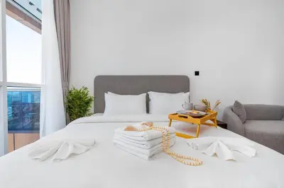 a bedroom with a white bed with a table at Nice studio in JVT - Al Manara Tower - Dubai in Dubai