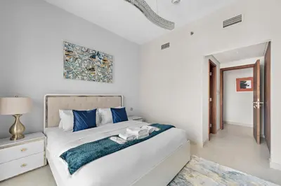 a white bedroom with a large bed with blue pillows at Brand New 2 Br Apartment In Family Community in Dubai