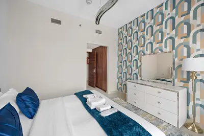 a bedroom with a bed with blue pillows and a mirror at Brand New 2 Br Apartment In Family Community in Dubai