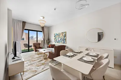a white living room with a table and chairs at Brand New 2 Br Apartment In Family Community in Dubai