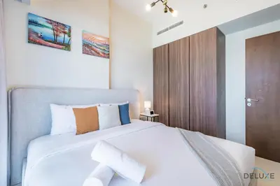 a bedroom with a white bed and a wooden door at Special Deal 2BR with Canal Views & Relaxing Balcony by Deluxe Holiday Homes in Dubai
