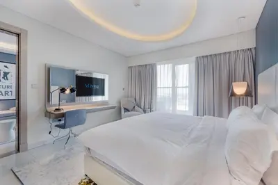 a white bedroom with a large bed and a desk at ALiving Modern & Chic 1BR I Paramount Tower D -2203 in Dubai