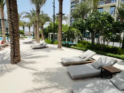 a patio with lounge chairs and palm trees at Creekside Bliss 1BR with Beach Access Summer 3 in Dubai