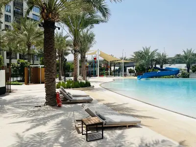 a resort swimming pool with chaise lounges and a slide at Creekside Bliss 1BR with Beach Access Summer 3 in Dubai