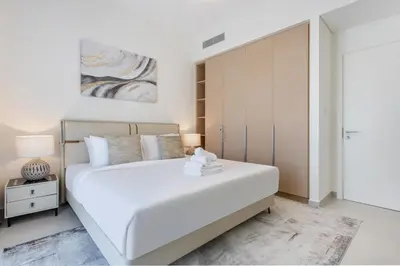 a white bedroom with a large bed and a closet at Creekside Bliss 1BR with Beach Access Summer 3 in Dubai
