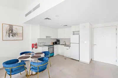 a kitchen with a table and blue chairs at A Living One 1BR Apartment At Asayel 3, Madinat Jumeirah in Dubai