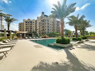 a resort swimming pool with chairs and palm trees at A Living One 1BR Apartment At Asayel 3, Madinat Jumeirah in Dubai