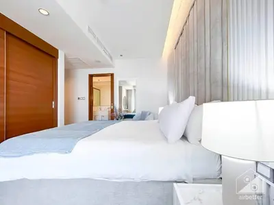 a bedroom with a large white bed with a wooden door at Dubai Mall Downtown Luxury stay with Balcony & View in Dubai