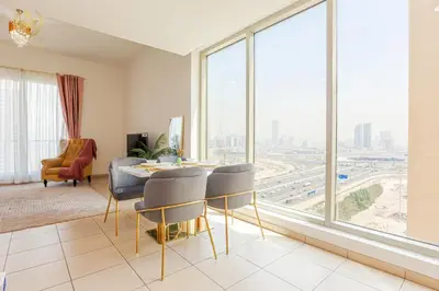 a living room with a table and chairs and a large window at Royalton - Tranquil 15th-Floor Apartment with City Views in Dubai