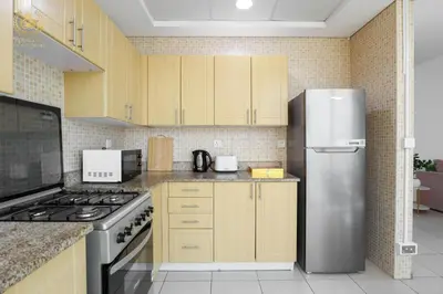 a kitchen with wooden cabinets and a stainless steel refrigerator at Royalton - Tranquil 15th-Floor Apartment with City Views in Dubai