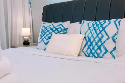 a white bed with blue and white pillows on it at WelHome - Opulent Retreat With Panoramic Cityscape Views in Dubai