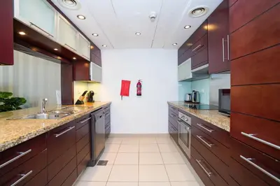 a large kitchen with wooden cabinets and a sink at Lovely 1BHK in Burj views tower near Dubai mall in Dubai