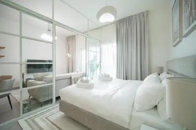 a white bedroom with a large bed and a mirror at SettlerHomes - Serene Golfville Escape near Parkside in Dubai