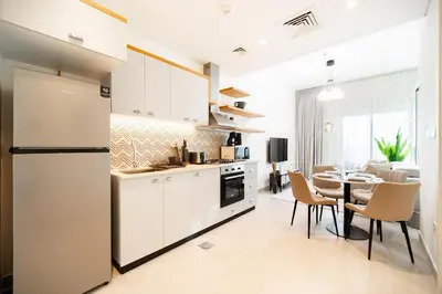 a kitchen and dining room with white cabinets and a table at SettlerHomes - Serene Golfville Escape near Parkside in Dubai