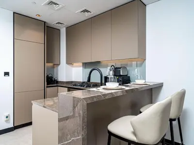 a kitchen with gray cabinets and white stools at Exceptional 1Bedroom with Premium Amenities in Dubai