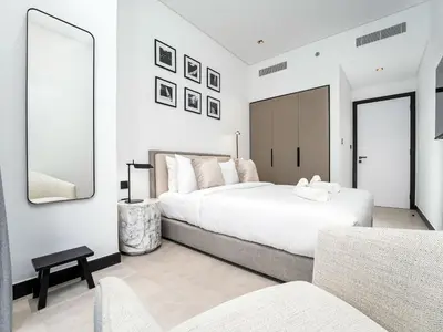 a white bedroom with a large bed and a mirror at Exceptional 1Bedroom with Premium Amenities in Dubai
