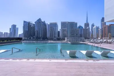 a large swimming pool with chairs and a city skyline at Exceptional 1Bedroom with Premium Amenities in Dubai