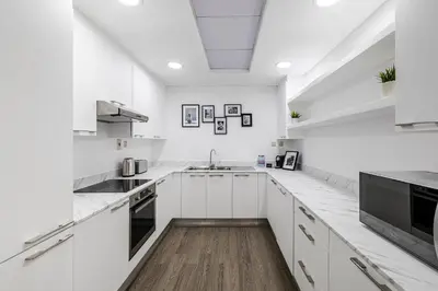 a white kitchen with white cabinets and a wooden floor at 2BR City View Bay Square B13 in Dubai