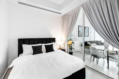a white bedroom with a large bed and a table at 2BR City View Bay Square B13 in Dubai