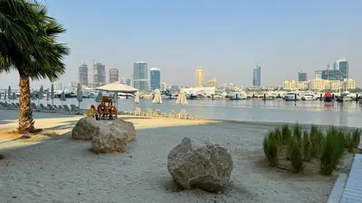 a beach with rocks in the sand and a city at SettlerHomes - Emaar Beachfront Haven With The Sea View in Dubai