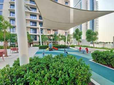 a playground in front of a tall building at SettlerHomes - Emaar Beachfront Haven With The Sea View in Dubai